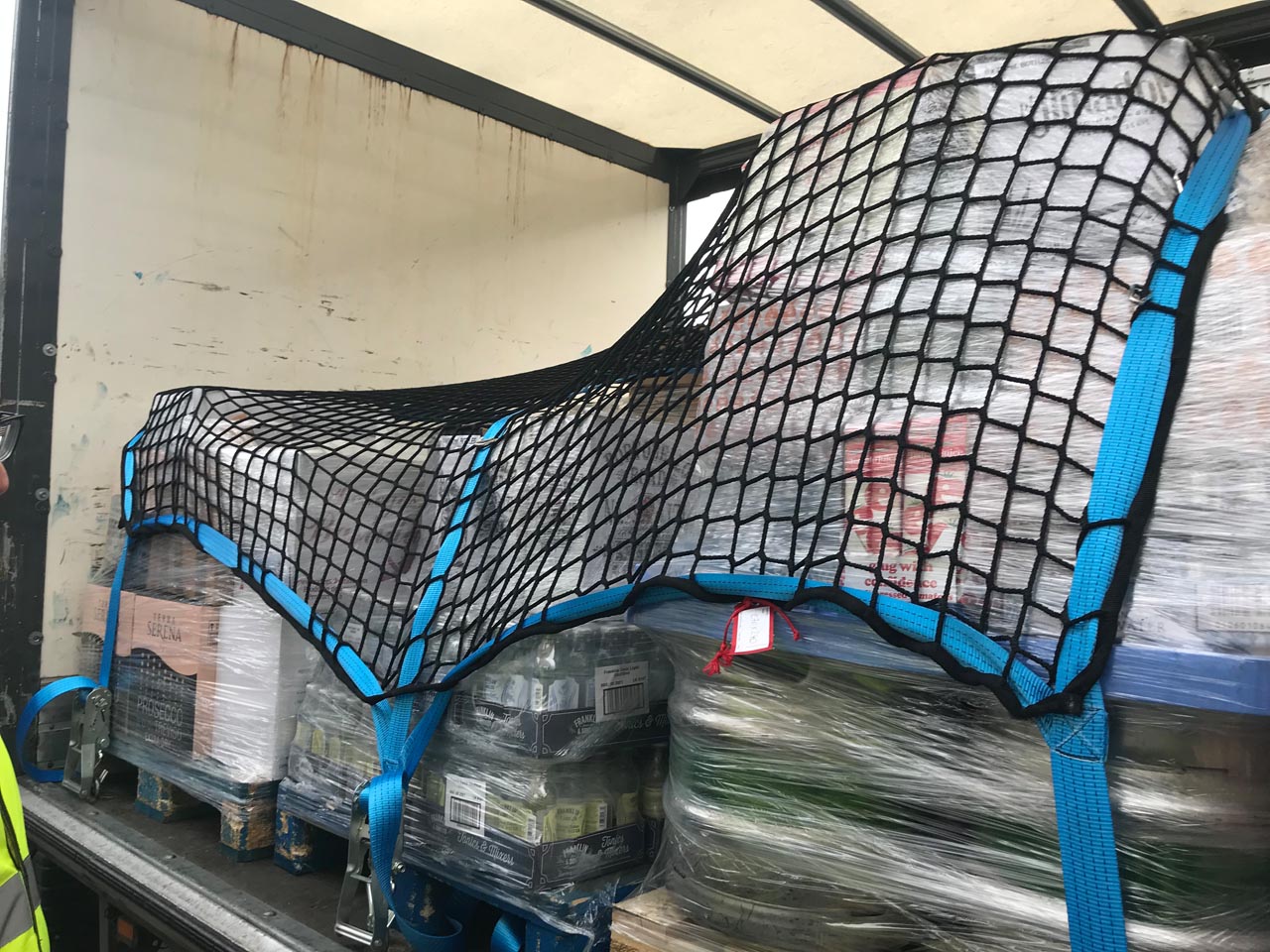 Heavy duty cargo net with webbing and integrated fittings in use as a pallet load control net.