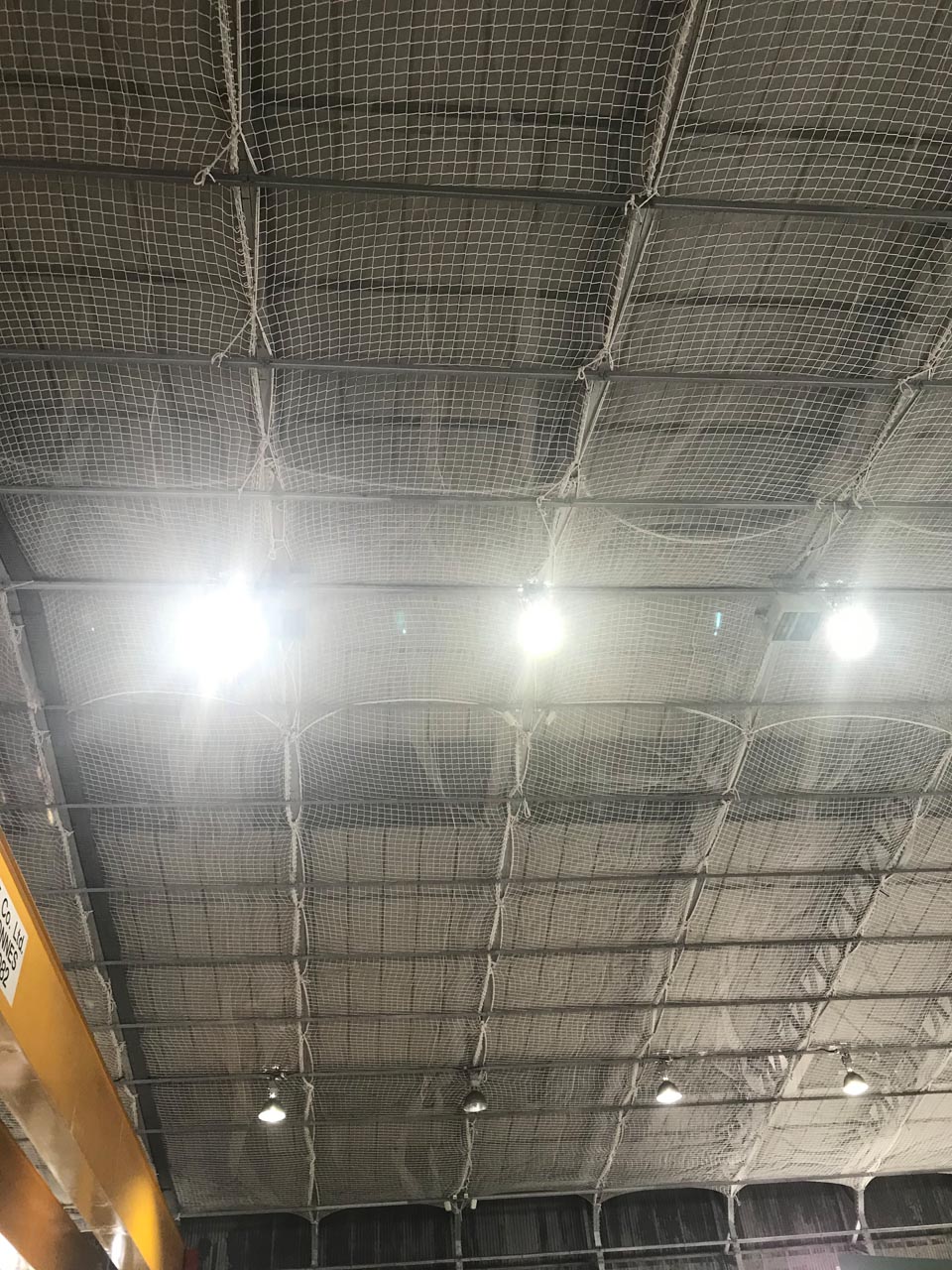 Safety netting under a roof inside a warehouse.